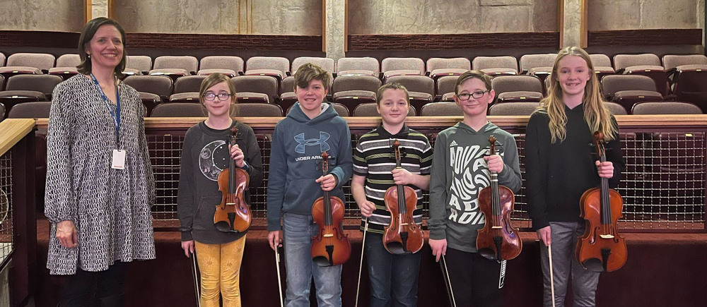Teacher and five students who are holding violins