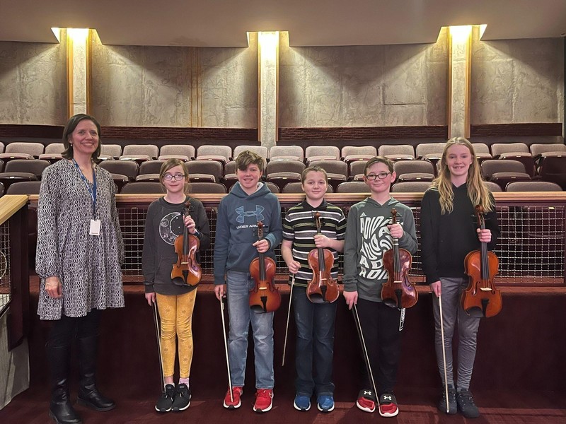 Teacher and five students who are holding violins