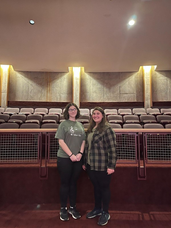 Two students standing together in auditorium