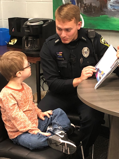 Officer Hopper reading to Chase, both sitting in chairs by a table